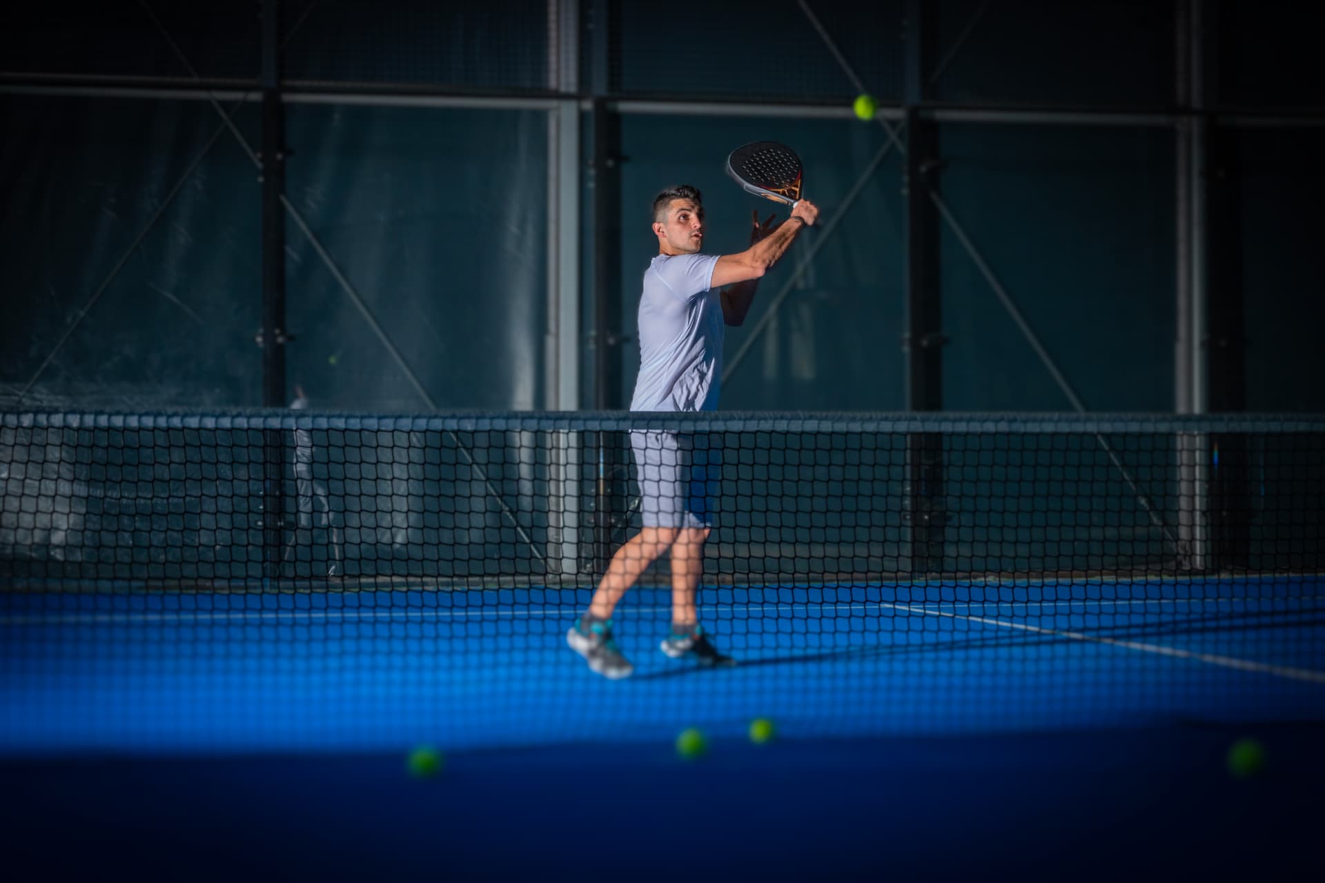 Joueur adulte frappant la balle sur une piste de padel indoor