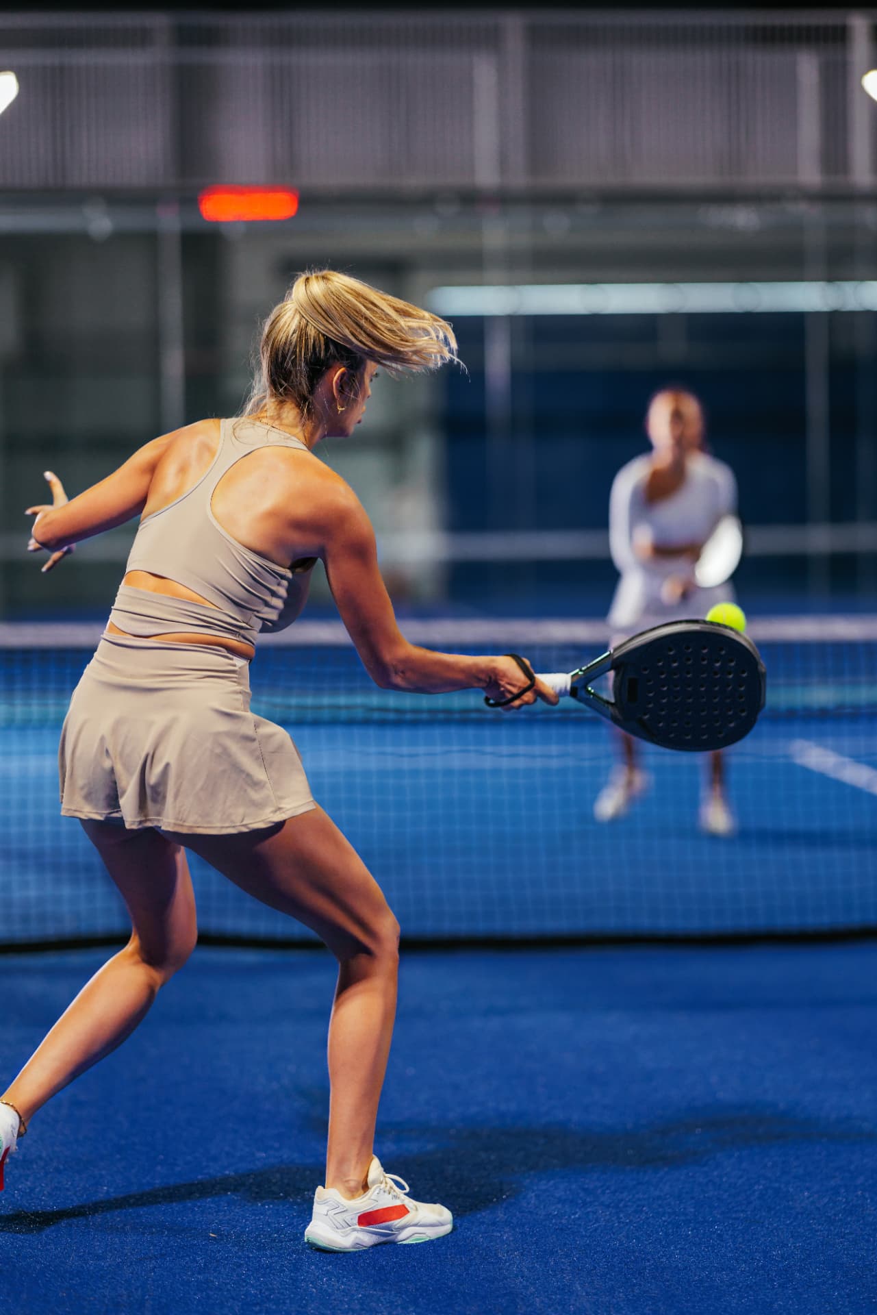 Joueuse de padel en action sur une piste indoor