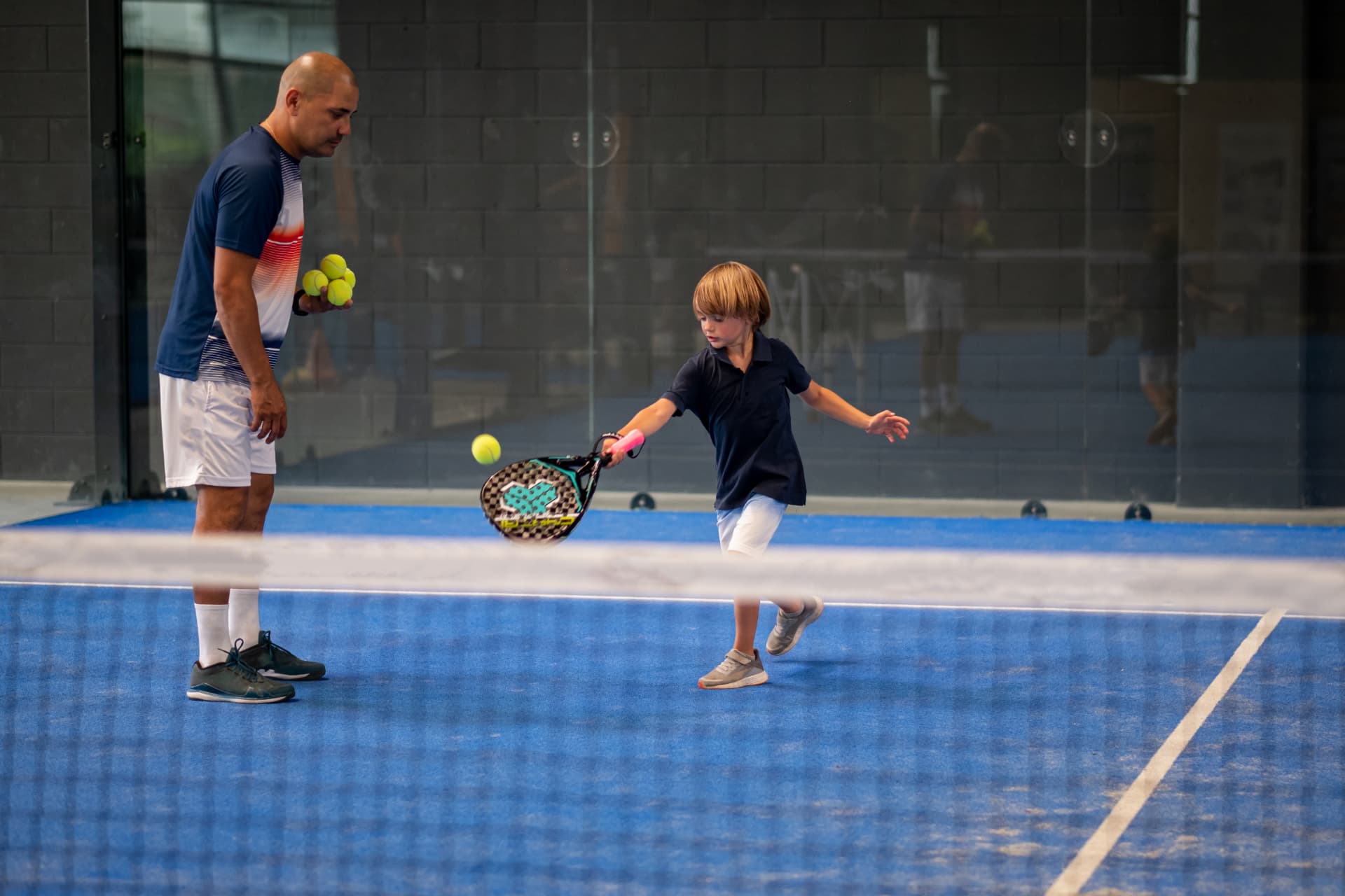 Enfant jouant au padel sur une piste indoor