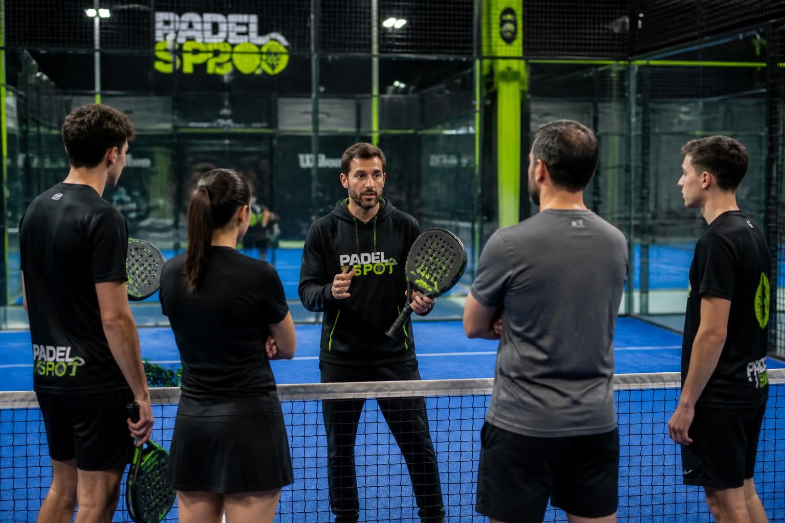 Coach de padel encadrant un groupe sur une piste indoor